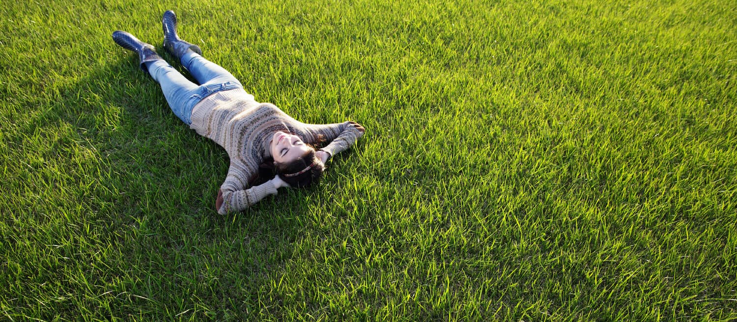 Woman relaxing on healthy green lawn in Minnetonka - stress-free lawn maintenance